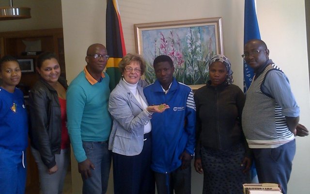Grade 8 Overstrand learner, Thabile Gquira (pictured centre) proudly shows off the gold medal he won at the recent National Indigenous games.  Thabile is flanked by Executive Mayor Nicolette Botha-Guthrie to his left and his guardian and sister, Ncediswa Gqira to his right.  Also in attendance were officials from the Western Cape Department of Cultural Affairs and Sport (DECAS).